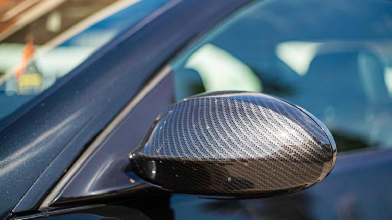 Blue car with a carbon-fibre wing mirror reflecting bright sunlight in Dubai